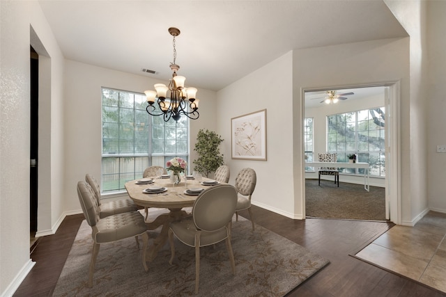 dining space with dark wood-type flooring, ceiling fan with notable chandelier, and a healthy amount of sunlight