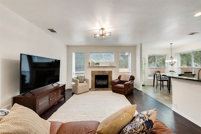 living room with a fireplace, dark hardwood / wood-style flooring, a textured ceiling, and an inviting chandelier