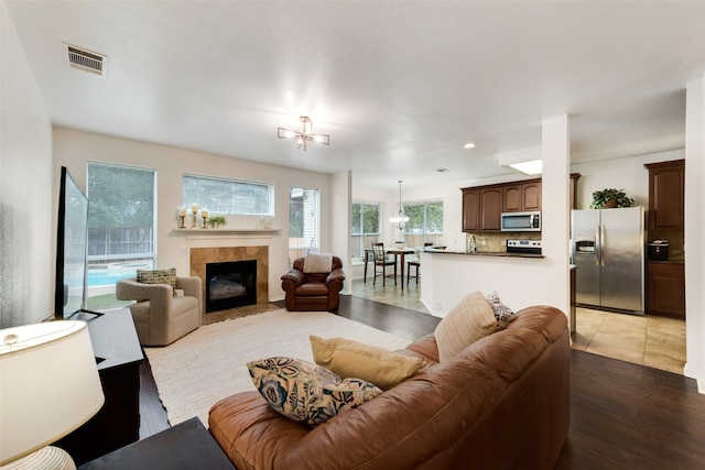 living room with sink, a tiled fireplace, a chandelier, and hardwood / wood-style floors