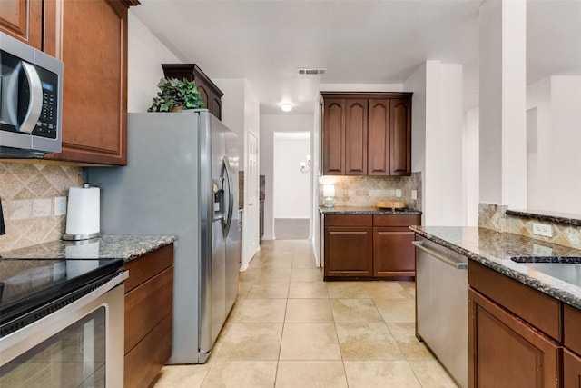 6002 Baldcypress Ct, Garland, TX 75043 - kitchen featuring stainless steel appliances, backsplash, dark stone countertops, and light tile patterned floors