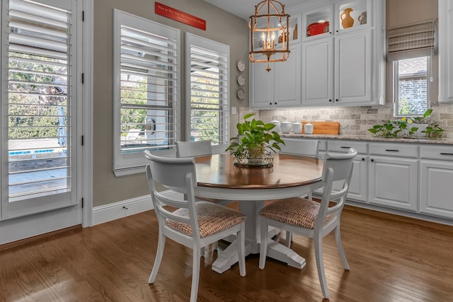 dining area featuring a notable chandelier, a healthy amount of sunlight, and dark hardwood / wood-style floors