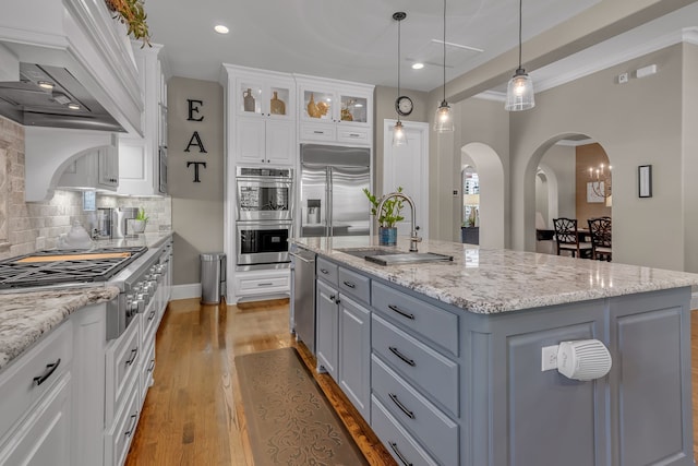 kitchen featuring white cabinetry, appliances with stainless steel finishes, hanging light fixtures, sink, and an island with sink