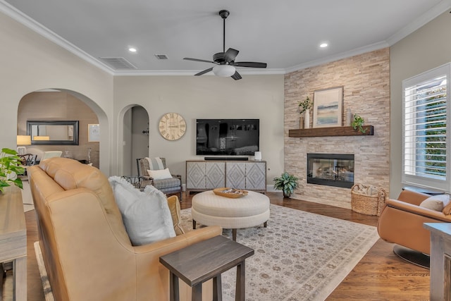 living room featuring ceiling fan, hardwood / wood-style floors, ornamental molding, and a fireplace