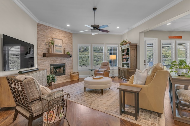 living room featuring hardwood / wood-style floors, a stone fireplace, ceiling fan, and ornamental molding