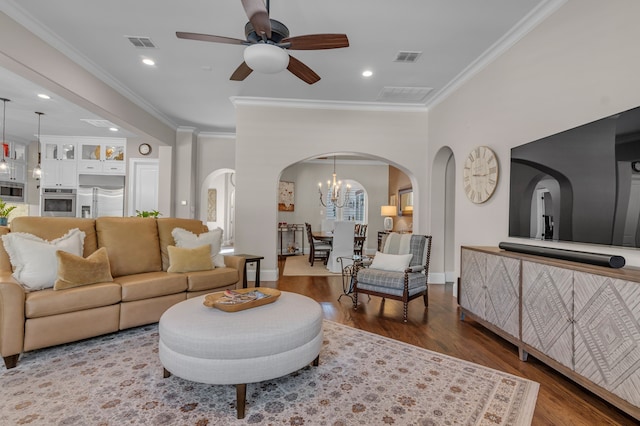 living room with plenty of natural light, hardwood / wood-style floors, ornamental molding, and ceiling fan with notable chandelier