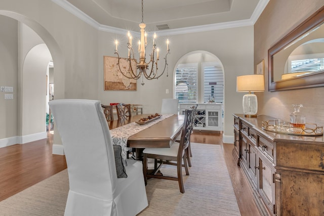 dining area with ornamental molding, light hardwood / wood-style flooring, and a tray ceiling