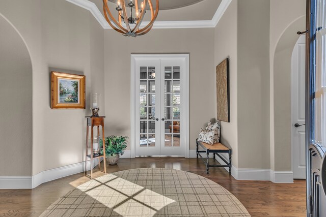 entryway featuring dark hardwood / wood-style flooring, an inviting chandelier, french doors, and ornamental molding