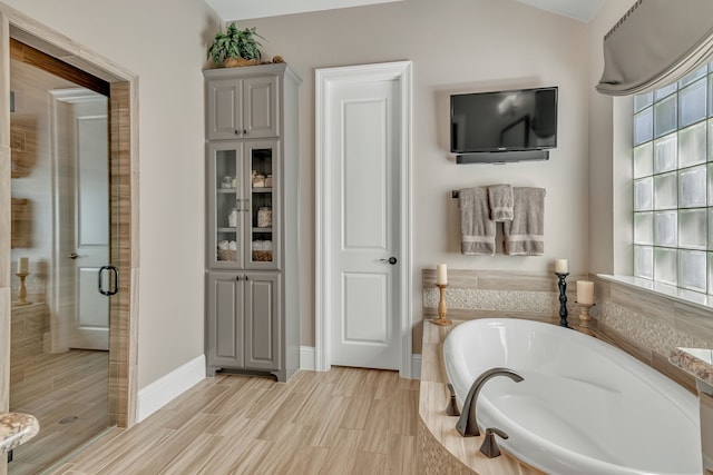 bathroom with vaulted ceiling, hardwood / wood-style flooring, and separate shower and tub