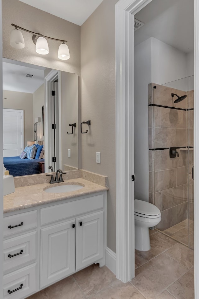 bathroom with toilet, vanity, tile patterned flooring, and tiled shower