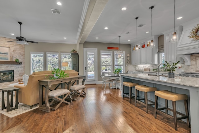 kitchen with decorative backsplash, plenty of natural light, hardwood / wood-style flooring, and light stone countertops