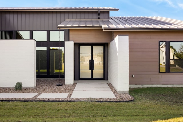 view of exterior entry with french doors and a yard