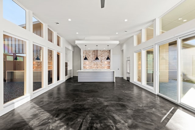 unfurnished living room with a high ceiling, plenty of natural light, and sink