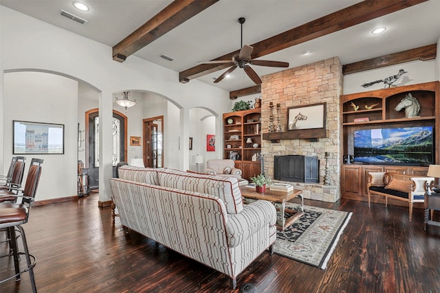 living room featuring dark hardwood / wood-style flooring, a fireplace, ceiling fan, and beam ceiling