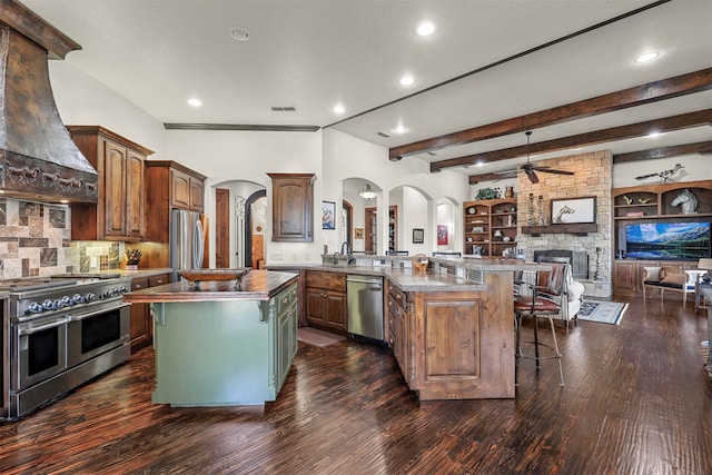 kitchen with a fireplace, stainless steel appliances, extractor fan, kitchen peninsula, and a center island