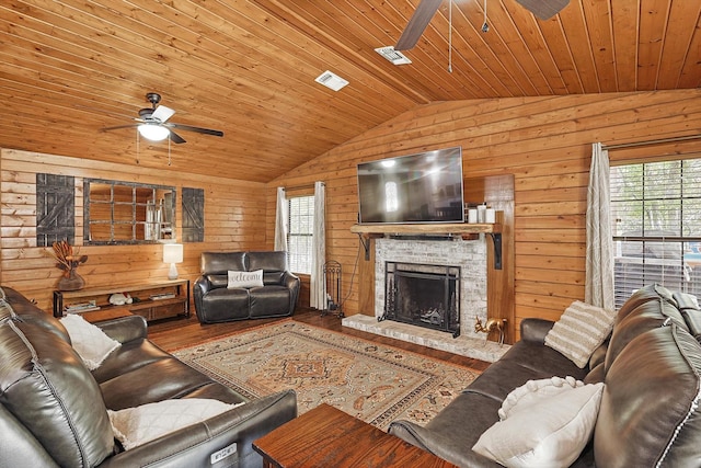 living room with wood-type flooring, a stone fireplace, wooden walls, and wood ceiling