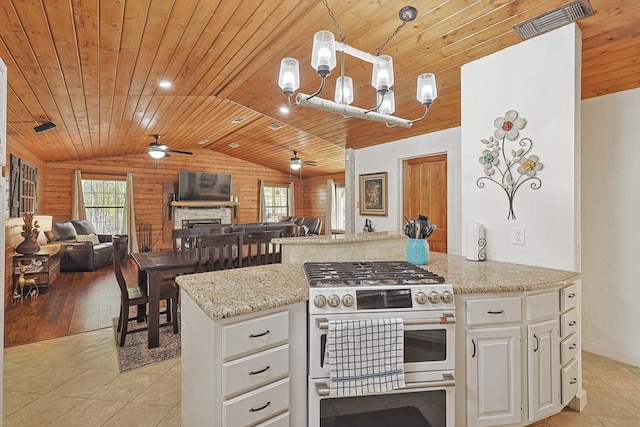 kitchen with light stone countertops, ceiling fan, high end stainless steel range oven, pendant lighting, and white cabinets