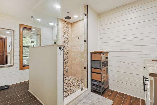 bathroom featuring wooden walls, vanity, and tiled shower