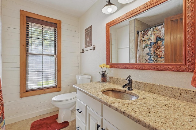 bathroom featuring wooden walls, tile patterned flooring, vanity, and toilet