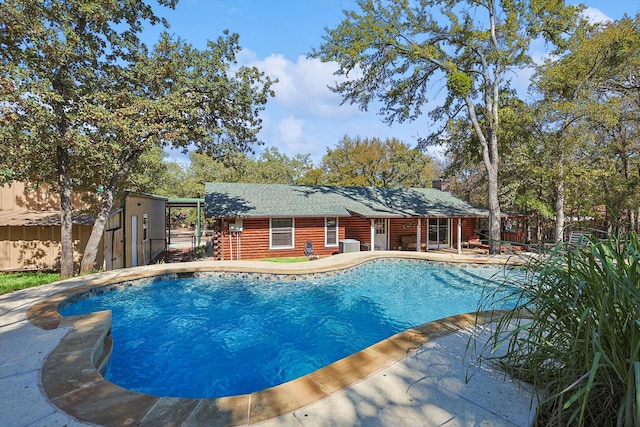 view of swimming pool with a patio and a storage shed