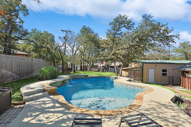 view of pool with pool water feature, an outbuilding, and a patio