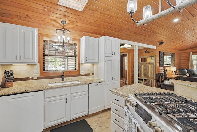 kitchen featuring white dishwasher, white cabinets, sink, high end stove, and decorative light fixtures