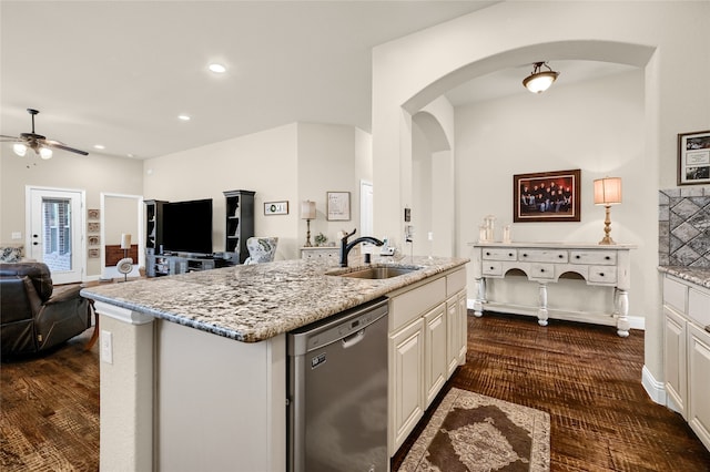 kitchen featuring a center island with sink, dishwasher, white cabinets, sink, and light stone countertops