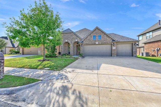 view of front of home featuring a garage, cooling unit, and a front lawn