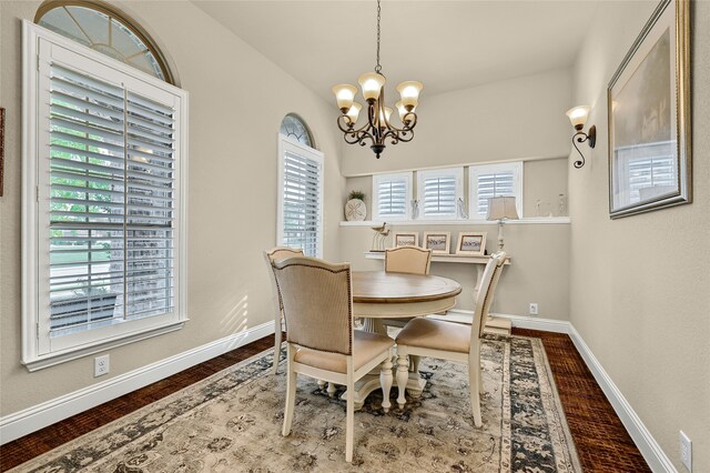 dining room with wood-type flooring, plenty of natural light, and an inviting chandelier