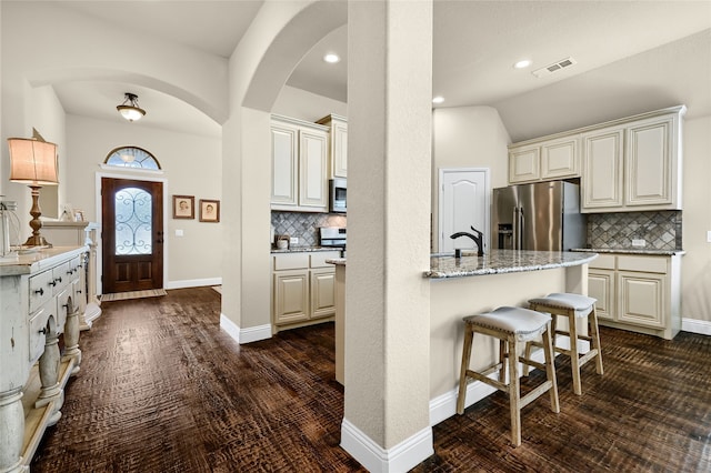 kitchen featuring dark hardwood / wood-style flooring, tasteful backsplash, light stone countertops, and stainless steel appliances