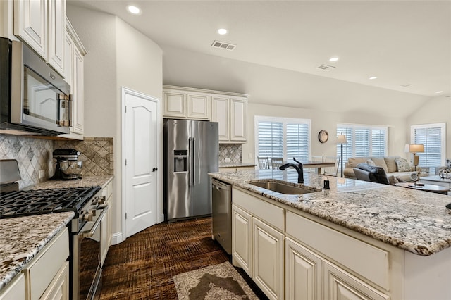 kitchen featuring stainless steel appliances, sink, an island with sink, vaulted ceiling, and decorative backsplash