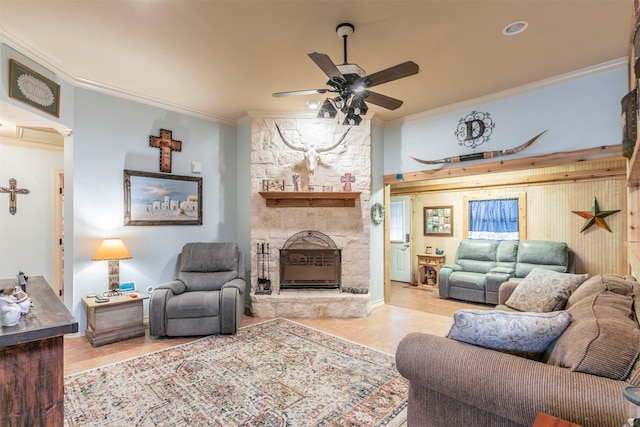 living room with a stone fireplace, light wood-type flooring, ceiling fan, and crown molding