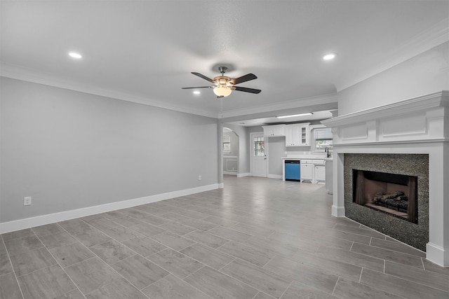 unfurnished living room with ceiling fan, sink, and crown molding