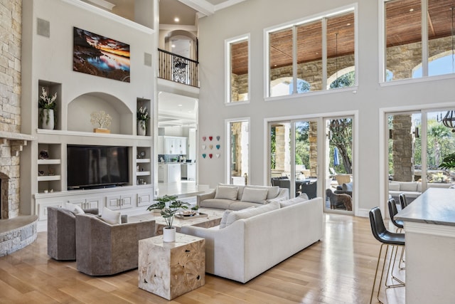 6800 Rainwood Dr, Plano, TX 75024 - living room featuring a towering ceiling, light wood-style floors, built in shelves, ornamental molding, and a fireplace