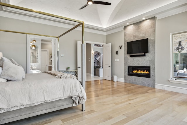 6800 Rainwood Dr, Plano, TX 75024 - bedroom with a tiled fireplace, wood finished floors, vaulted ceiling, crown molding, and ensuite bath