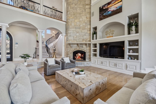 6800 Rainwood Dr, Plano, TX 75024 - living area with ornate columns, stairway, wood finished floors, a towering ceiling, and a stone fireplace
