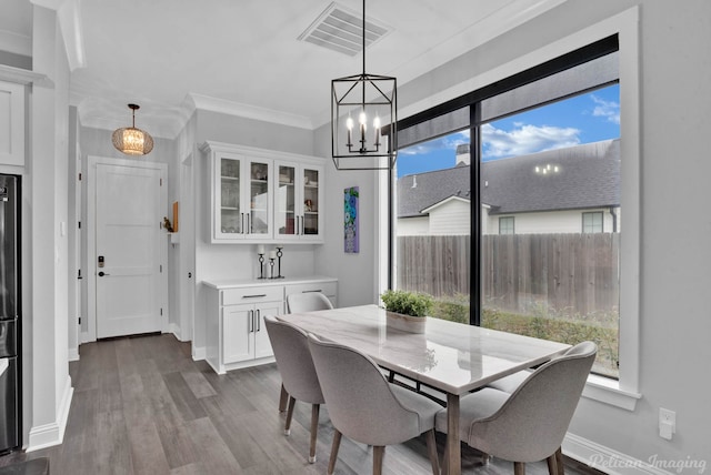 dining space featuring hardwood / wood-style flooring, crown molding, and a notable chandelier