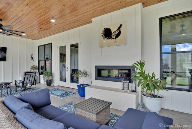 view of patio / terrace with an outdoor living space with a fireplace, ceiling fan, and french doors