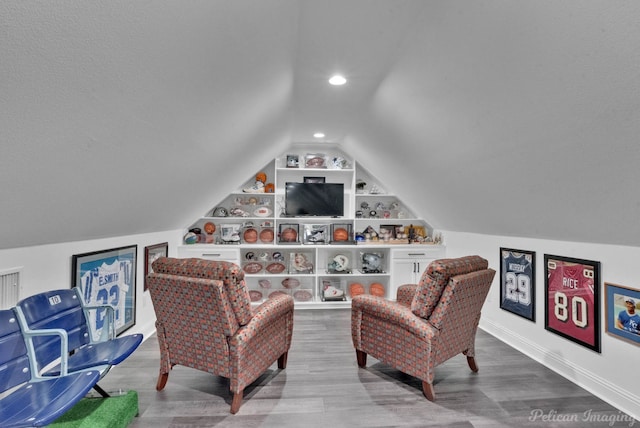 sitting room with lofted ceiling, built in shelves, and wood-type flooring