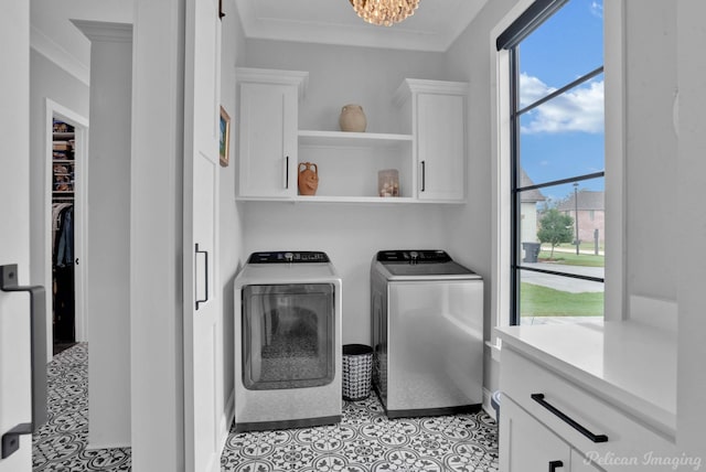 washroom with cabinets, an inviting chandelier, washer and clothes dryer, and crown molding