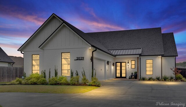 modern inspired farmhouse featuring a garage, a front yard, and french doors