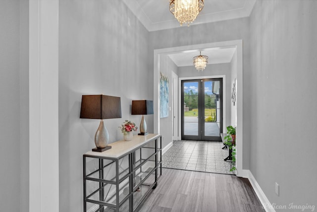 entryway with a notable chandelier, wood-type flooring, ornamental molding, and french doors