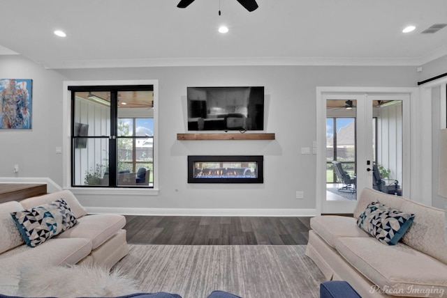 living room with crown molding, plenty of natural light, ceiling fan, and dark hardwood / wood-style flooring