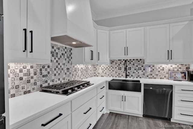 kitchen with hardwood / wood-style floors, backsplash, custom range hood, white cabinetry, and stainless steel appliances