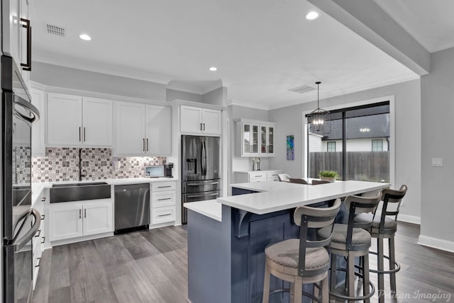 kitchen featuring hanging light fixtures, stainless steel appliances, a kitchen island, dark hardwood / wood-style floors, and white cabinets