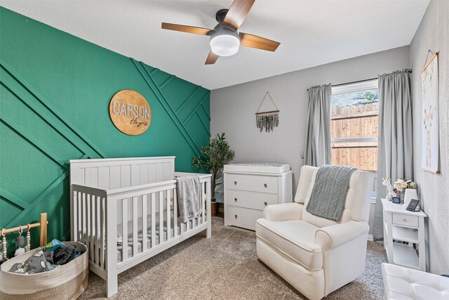 carpeted bedroom with a nursery area and ceiling fan