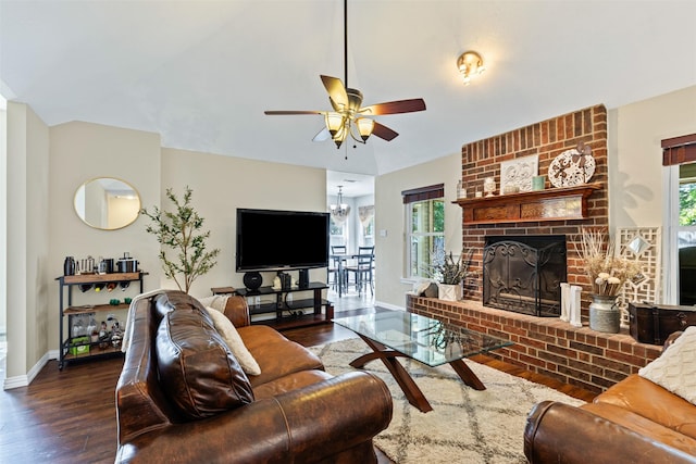 living room with dark hardwood / wood-style flooring, a brick fireplace, and ceiling fan with notable chandelier