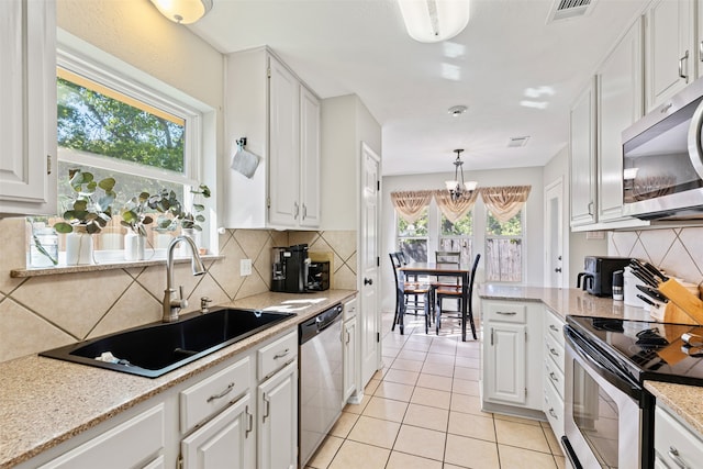 kitchen with stainless steel appliances, white cabinetry, and plenty of natural light