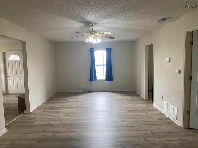 spare room featuring hardwood / wood-style flooring, ceiling fan, and a textured ceiling