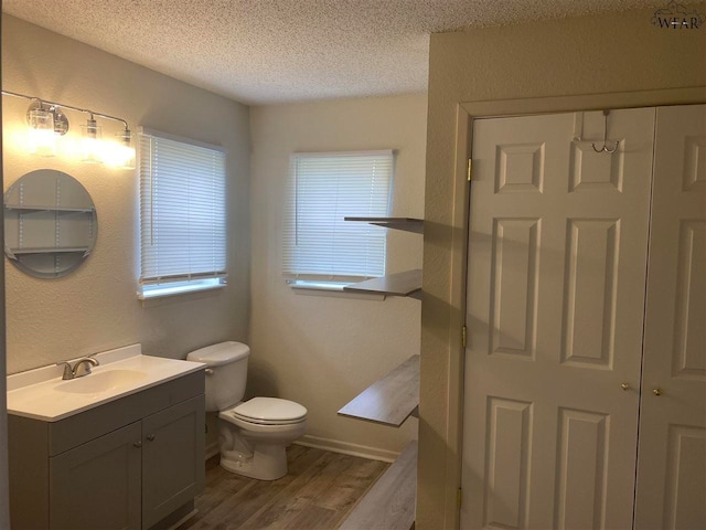 bathroom with toilet, vanity, hardwood / wood-style floors, and a textured ceiling