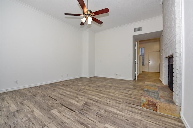 unfurnished living room with a brick fireplace, crown molding, ceiling fan, and light hardwood / wood-style flooring